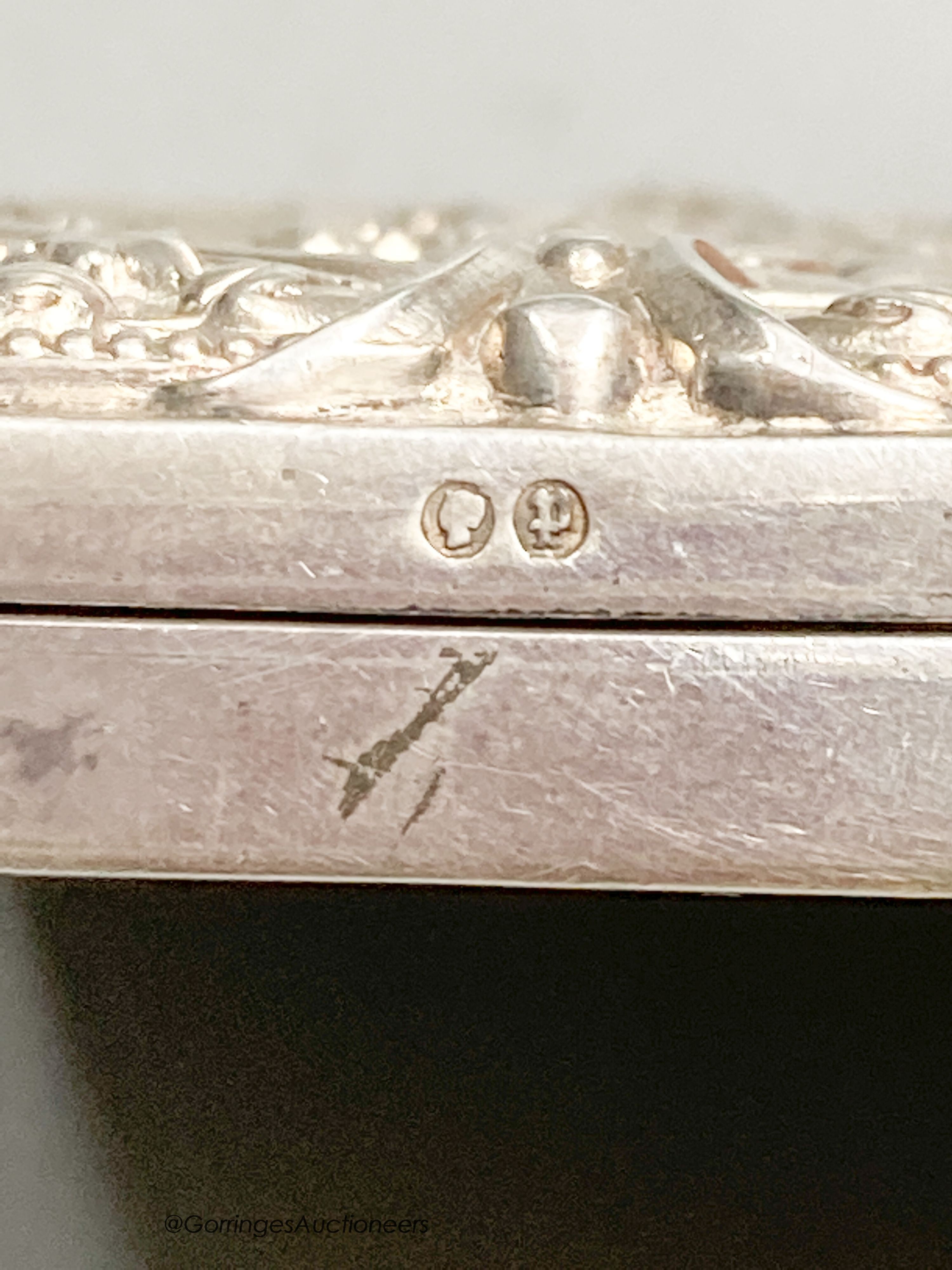 A late Victorian embossed silver shaped rectangular cigarette case, with mirrored interior, Birmingham, 1889, 81mm.